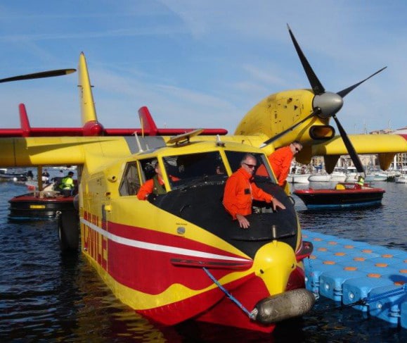 Deux hommes debout à côté d'un avion jaune et rouge lors d'un raid.
