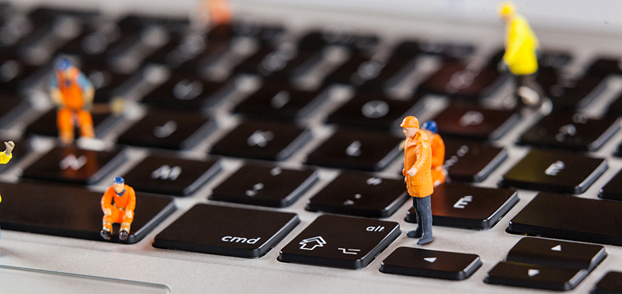 Travailleurs de la construction miniatures sur un clavier d'ordinateur portable.
