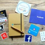 Un cahier, un stylo et des autocollants de médias sociaux sur une table en bois.