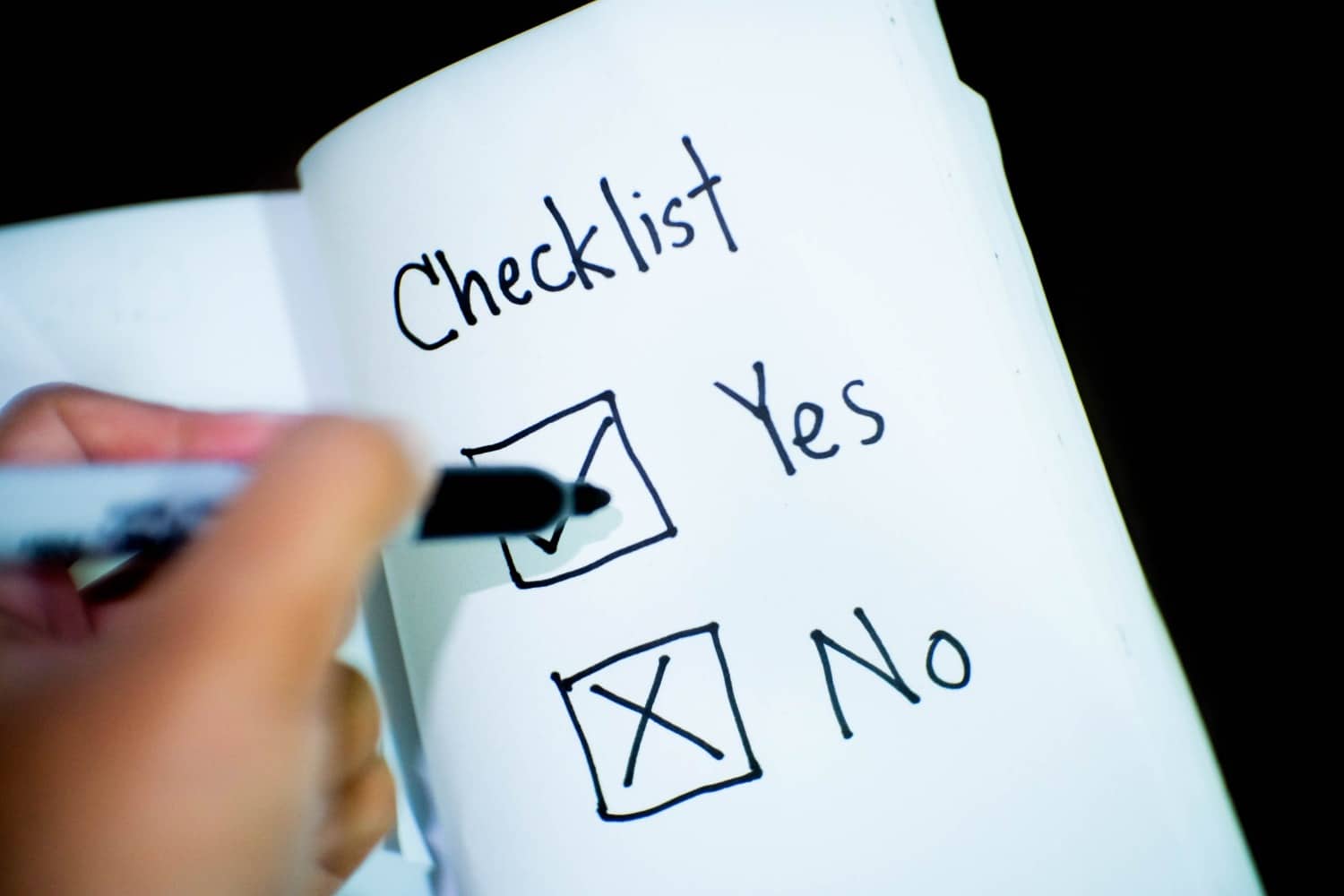 Une personne rédigeant une check-list sur papier pour la conformité RGPD.
