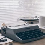 Une machine à écrire et une tasse de café occupent un bureau.
