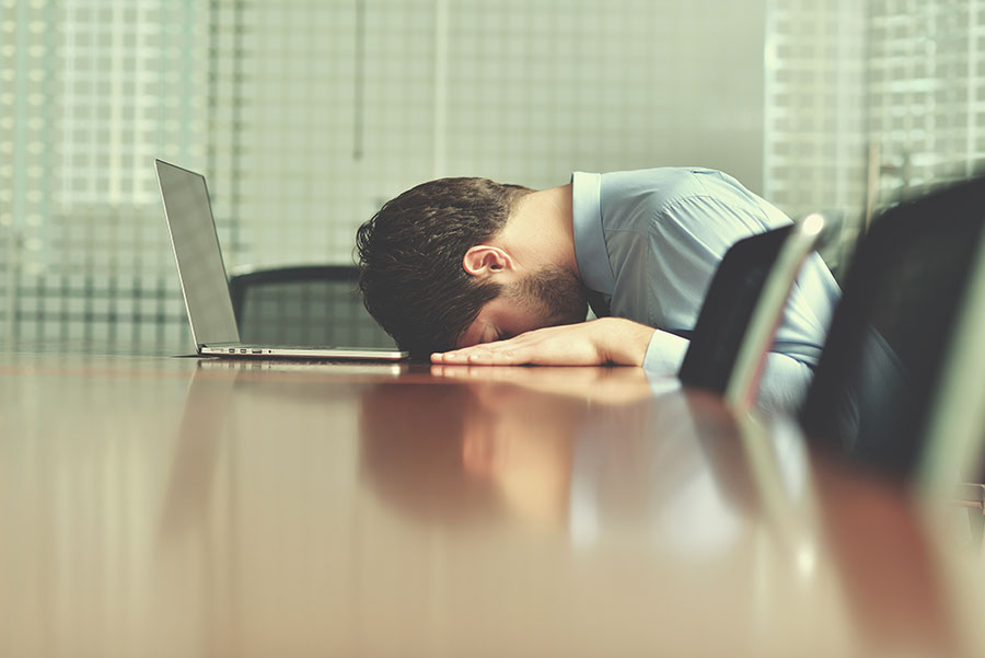 La tête d'un homme repose sur une table en bois lors de l'utilisation de Wordpress 5.0.