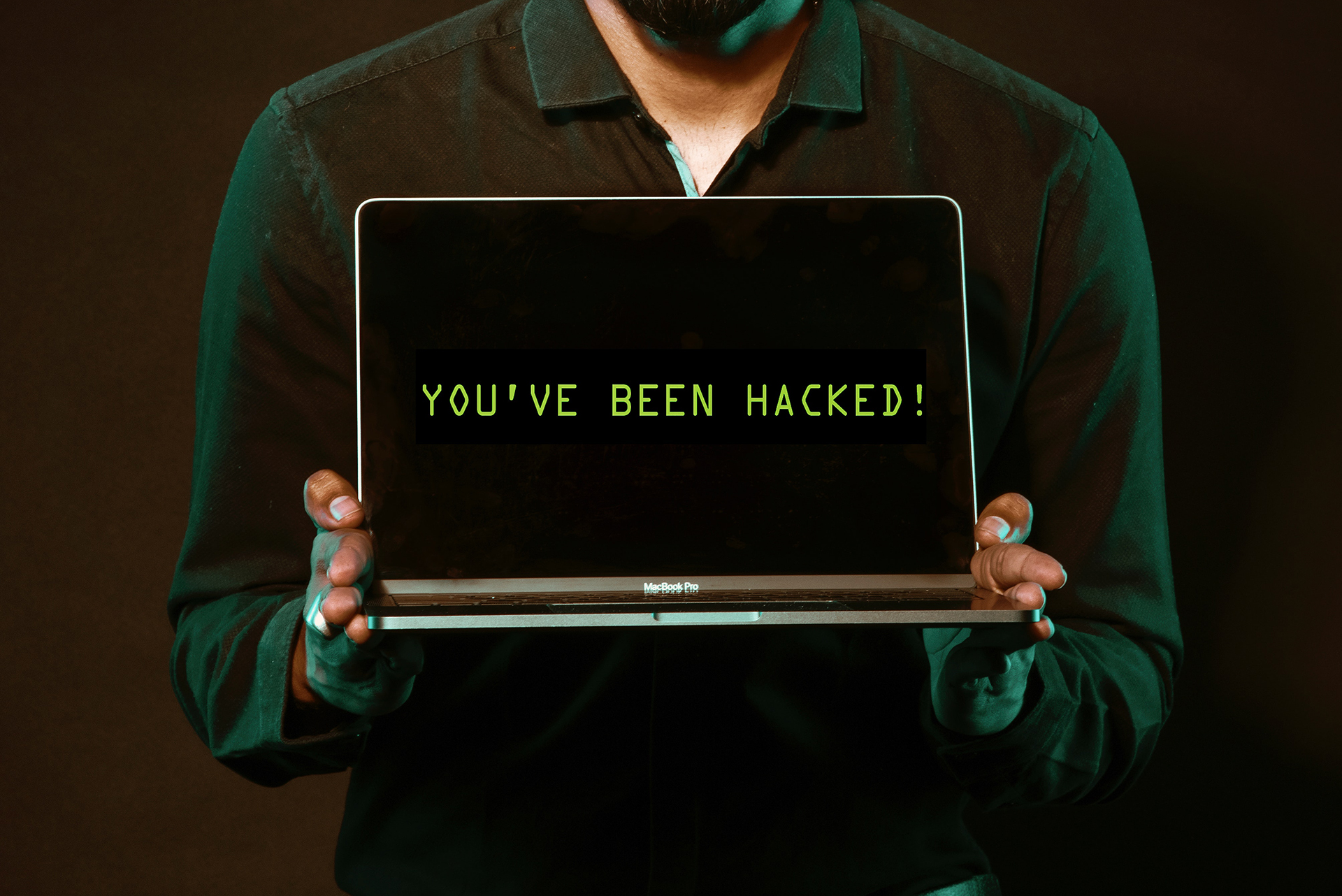 Un homme tenant un ordinateur portable affichant un message d'alerte indiquant une attaque WordPress réussie.