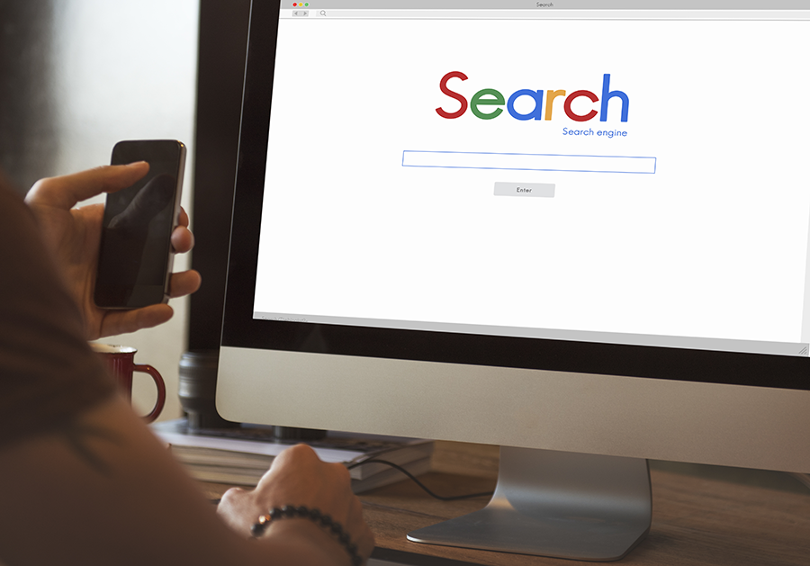 Un homme naviguant sur Internet avec une requête de recherche sur son écran d'ordinateur.