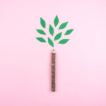 Un crayon avec une feuille verte montrant sa faible empreinte carbone sur un fond rose vif.